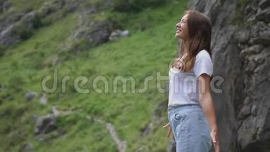 站在山顶上的漂亮女孩举起双手欣赏风景。 慢动作